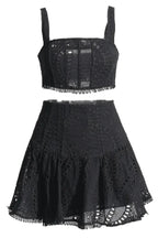 Black embroidered eyelet crop top and flared skirt set laid flat.