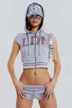 Model wearing a gray cropped zip-up hoodie with short sleeves and sequin embellishments on the front, accessorized with a denim cap and sunglasses.