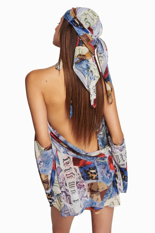 Back view of a woman in a collage print mini dress with an open back and long sleeves.