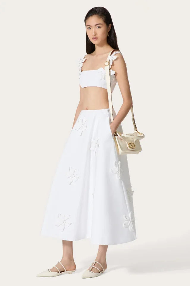 Woman wearing a white floral applique cropped top and A-line skirt with white pointed flats Main image