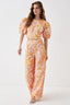 Model wearing a two-piece set with a cropped top and wide-leg pants featuring a floral lace overlay in orange, pink, and yellow.