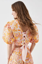 Back view of the cropped top, highlighting the lace-up detail with pink ribbon.