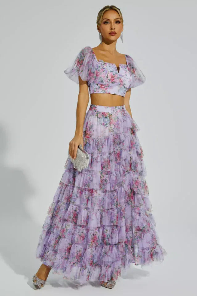 Woman wearing a floral print two-piece set with a crop top and tiered maxi skirt. Main image