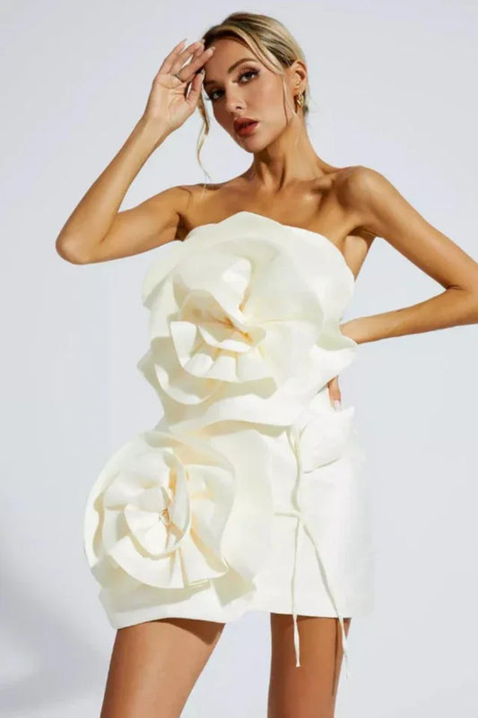 Woman wearing a white strapless mini dress with large floral appliqués on the bodice and skirt.