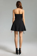 Back view of a black mini dress with thin spaghetti straps and a flared skirt