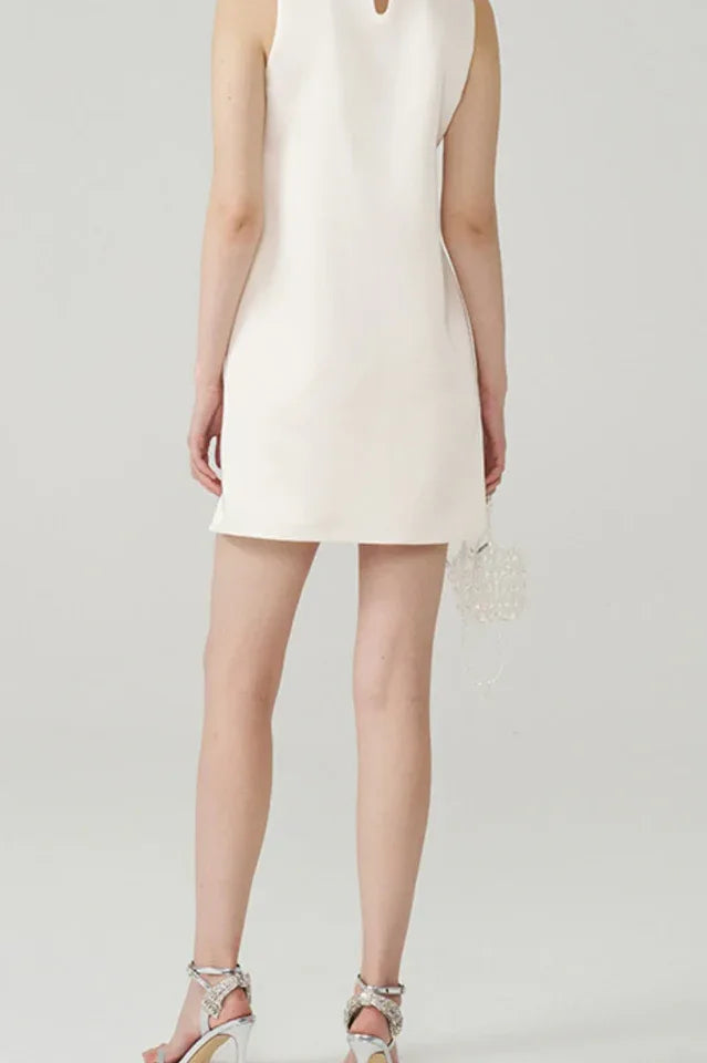 Back view of a model in an ivory A-line mini dress, highlighting the simple silhouette and the embellished collar from the front.