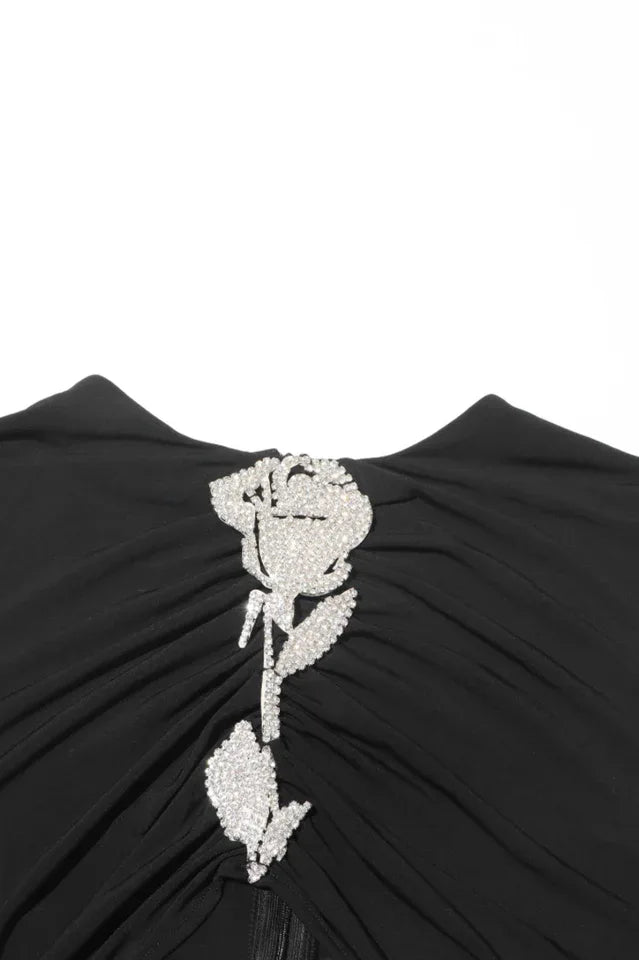 Close-up of the embellished rose detail on the bodice of a black velvet gown.