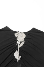 Close-up of the embellished rose detail on the bodice of a black velvet gown.