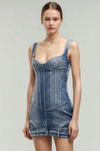 Model wearing a blue denim corset mini dress with strap shoulders, viewed from the front.