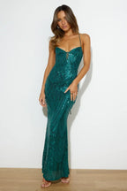 Full-length view of a woman in an emerald green sequined evening dress.