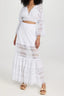 Woman wearing a white lace cropped blouse and matching white lace maxi skirt, standing against a white background.