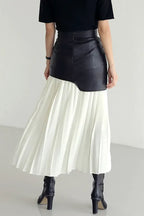 Back view of a black and white paneled pleated skirt with black boots