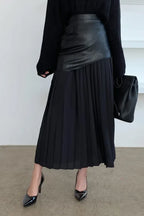 Model wearing a black paneled pleated skirt with black sweater and black heels