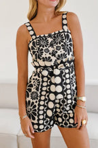 Woman wearing a black and white floral print romper with a square neckline and shorts.