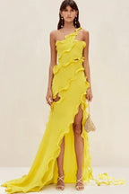 Model wearing a bright yellow one-shoulder chiffon gown with ruffled detailing and a high slit, showcasing the dress from the front.
