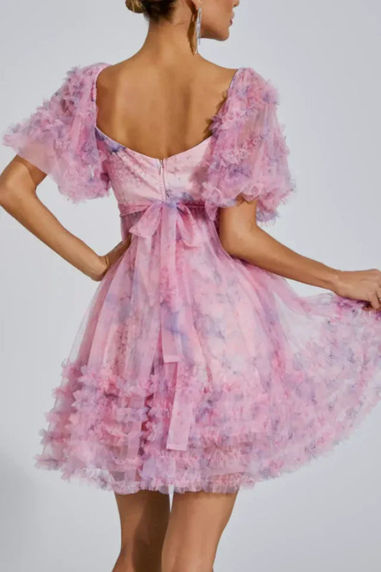 Back view of a pink floral print tulle dress with puff sleeves and a bow detail at the back.
