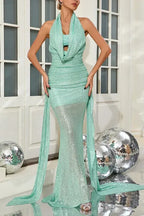 Side view of a woman in a mint green sequined halter neck mermaid gown with a draped cowl neck and train