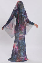 Back view of a woman in a shimmering galaxy dress with a dramatic sheer cape.