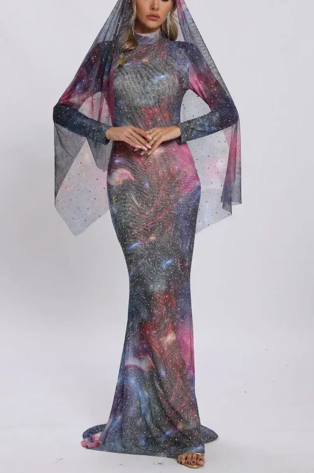 Woman wearing a long, form-fitting galaxy print dress with a sheer cape overlay and sparkle embellishments. Main image
