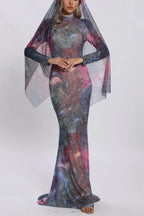 Woman wearing a long, form-fitting galaxy print dress with a sheer cape overlay and sparkle embellishments.