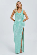 Woman wearing a shimmering mint green sequined column gown with a high slit and cowl neckline.