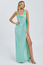 Full-length view of a woman in a mint green sequined gown with a high slit and asymmetrical neckline.
