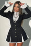 Woman wearing a black blazer dress with white ruffled cuffs and collar