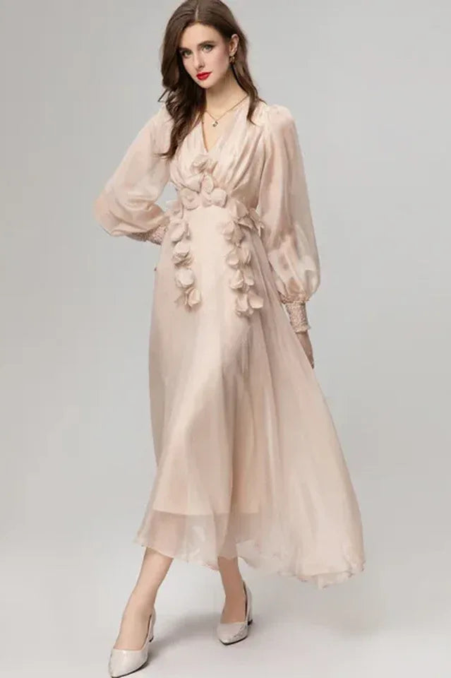 Woman wearing a long pale pink chiffon dress with floral appliqués and bishop sleeves