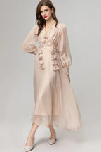 Woman wearing a long pale pink chiffon dress with floral appliqués and bishop sleeves