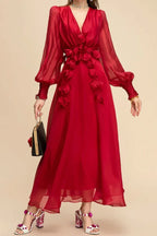 Woman holding a black clutch and wearing a red chiffon dress with floral appliqués and bishop sleeves