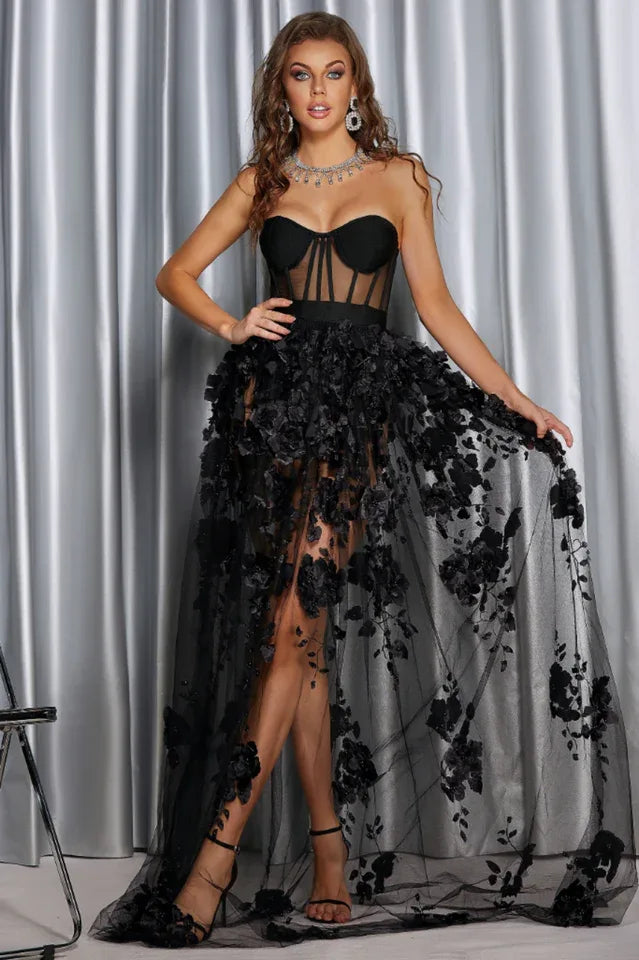 Full-length view of a woman wearing a black formal dress with a sweetheart neckline and floral overlay