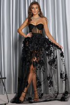 Full-length view of a woman wearing a black formal dress with a sweetheart neckline and floral overlay