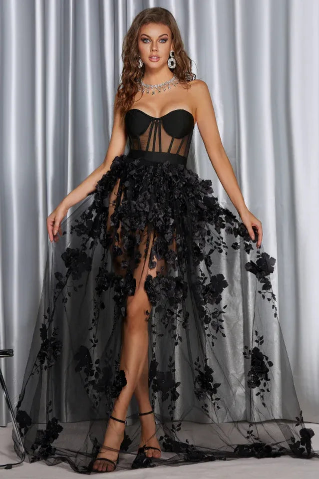 Woman in a black strapless formal gown with a sheer, floral-embellished skirt Main image