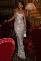 woman in a glittery silver evening dress seated on a red velvet chair