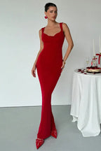 Woman wearing a fitted red maxi dress with a cowl neckline and red bow shoes.