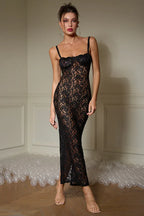 Woman wearing a black lace maxi dress with spaghetti straps and a high slit.