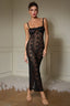 Woman wearing a black lace maxi dress with spaghetti straps and a high slit.