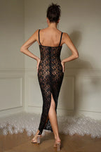 Back view of a woman wearing a black lace maxi dress with a high slit.