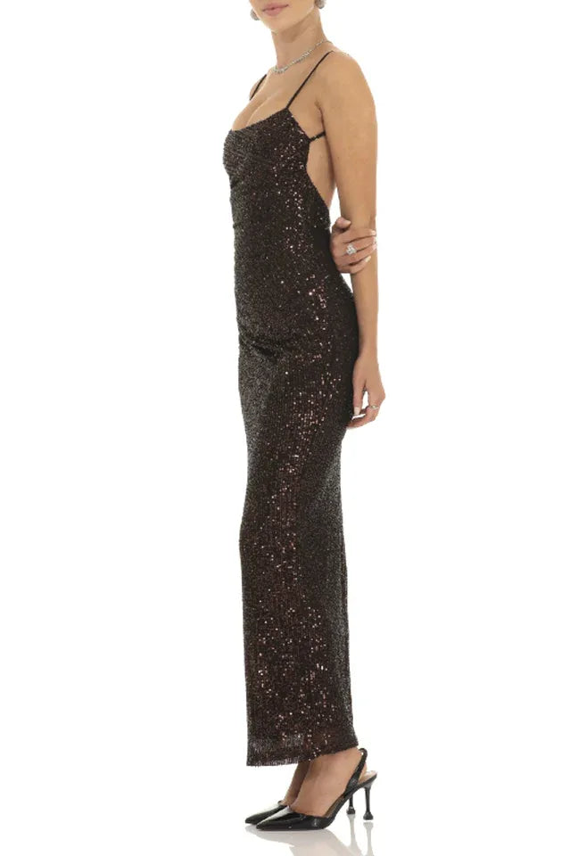 Woman wearing a floor-length dark sequined dress with spaghetti straps and a sweetheart neckline, side view