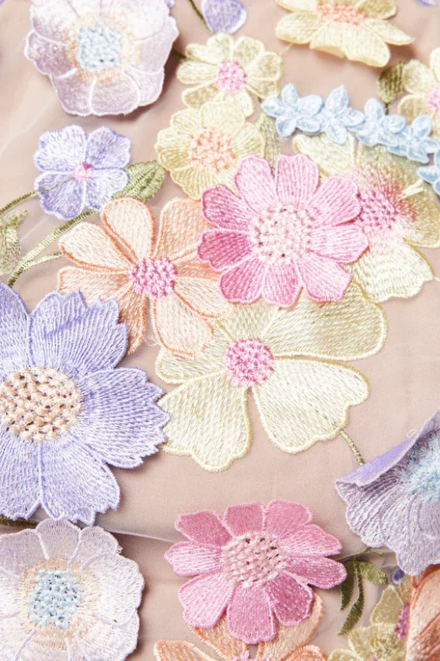 Detailed close-up of the 3D floral applique and embroidery on the fabric of a garment.