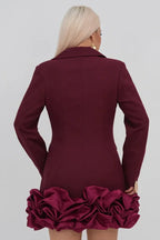 Back view of a woman in a maroon double-breasted blazer dress with a ruffled hem
