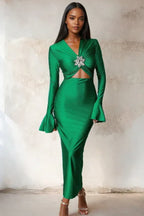 Woman wearing a long green satin dress with long flared sleeves and a cutout waist