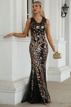 Woman posing in a black and gold sequined sleeveless mermaid dress.