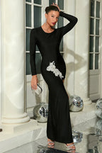 Full-length shot of a woman in a black formal dress featuring a dramatic slit and sparkling accents.