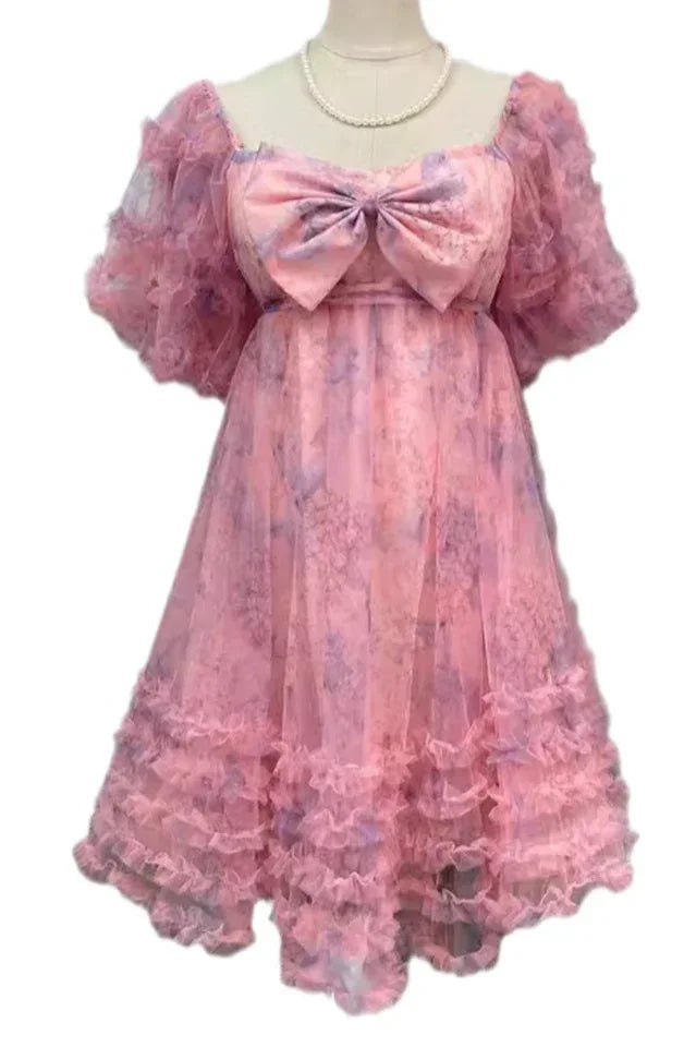 Pink floral print tulle dress with puff sleeves and a large bow detail on the bust, displayed on a mannequin.