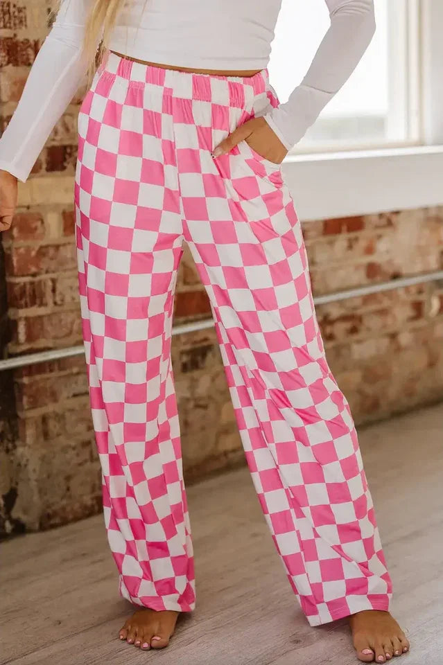 Close-up of a young woman's legs wearing pink and white checkerboard wide leg pants with pockets.
