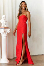 Full view of a woman in a red formal dress with a thigh-high slit showcasing her leg.
