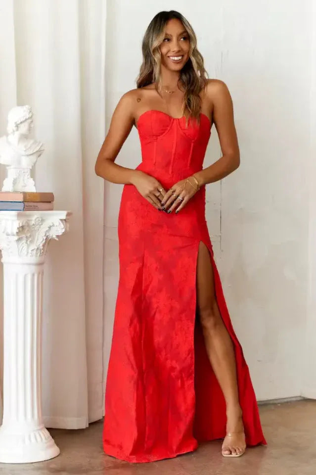 Woman wearing a long red strapless dress with a high leg slit and textured fabric. Main image