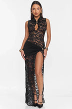 Woman wearing a black lace maxi dress with a high neckline and a thigh-high slit, front view.