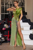 Full-length view of a model in a green sequined gown with chain embellishments and a high slit.